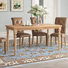 a dining room table with chairs and a rug on the floor in front of it