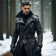 a man in black leather coat and gloves standing in the middle of a snowy forest