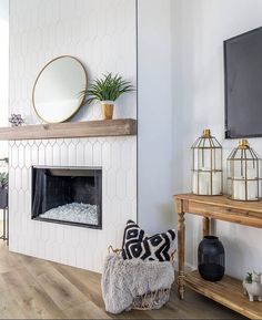 a living room with a fireplace, mirror and other decorations on the wall above it