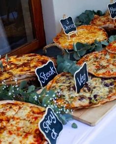 several pizzas with signs on them sitting on a table