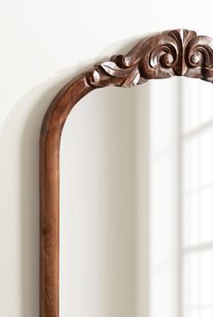 an ornate wooden mirror hanging on the wall