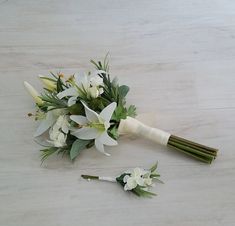 a bridal bouquet with white flowers and greenery on the floor next to it