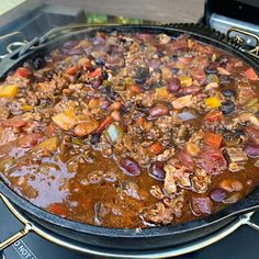 a large pan filled with meat and vegetables on top of an electric stovetop oven