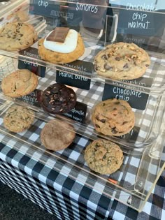 a display case filled with lots of different types of cookies and chocolate chip cookies on top of a checkered table cloth