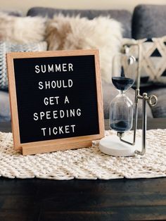 a sign that says summer should get a speeding ticket next to an hourglass on a table