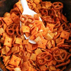 a spoon full of cheetos sitting in a crock pot filled with them