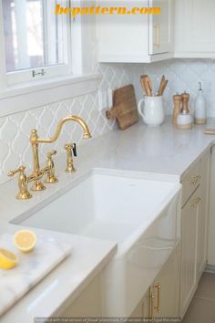 a kitchen with white cabinets and gold faucets