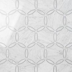 a white marble wall with an intricate design on the top and bottom, as well as grey circles