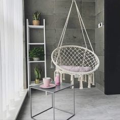 a hammock hanging from the ceiling in a room with grey walls and flooring