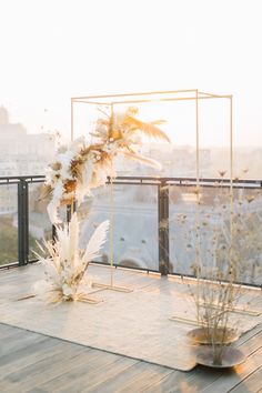 an outdoor ceremony setup with white flowers and greenery on a wooden deck overlooking the city