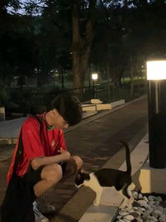 a man sitting on a bench next to a black and white cat in front of him