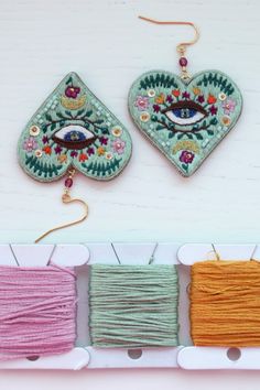 three spools of thread are next to each other on a white shelf with two hearts