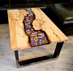 a table with flowers painted on it in the shape of a river running through wood