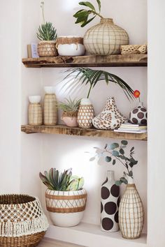 three wooden shelves with plants and vases on them