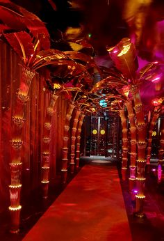 a long red carpeted hallway with tall columns and lights on the ceiling is lit up at night