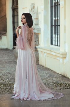 a woman in a pink dress is standing on the street with her back to the camera