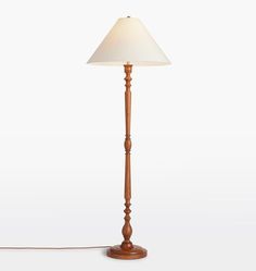 a wooden floor lamp with a white shade on the base and a cord attached to it