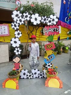 a young boy is standing in front of some fake plants and decorations for sports day