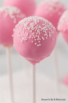 some pink cake pops with white sprinkles on them are ready to be eaten