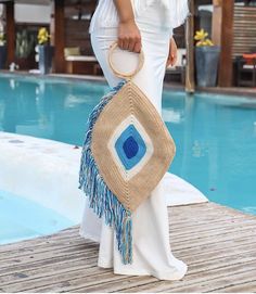 a woman is standing on a dock holding a handbag in front of a pool