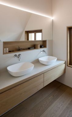 a bathroom with two sinks and mirrors on the wall next to each other in front of a window