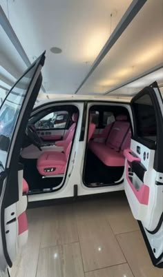 the interior of a white and pink car with its doors open in a showroom