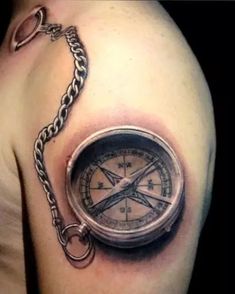 a man's arm with a compass tattoo on it and a chain around the arm