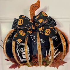 a decorated pumpkin hanging from the front door with halloween decorations on it's side