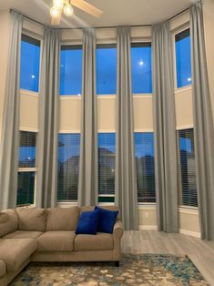 a living room filled with furniture and windows covered in blue curtains on top of them