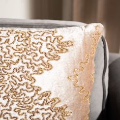 a gold and white pillow sitting on top of a gray couch