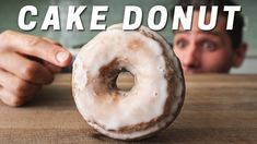 a donut sitting on top of a wooden table next to a man's face