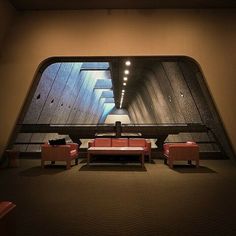 an empty room with couches and chairs in front of a large window that looks like a tunnel