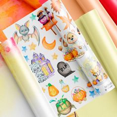 an assortment of halloween themed stickers on top of a paper with colored papers in the background