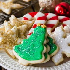 christmas cookies decorated with green and white icing on a plate next to other holiday decorations