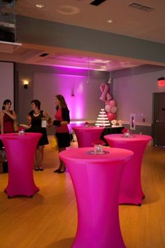 people are standing around in a room with pink tables and stools on the floor