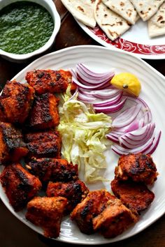 some food is on a white plate with red onions and lettuce next to pita bread