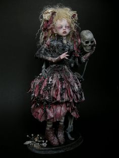 a creepy doll holding a skull in her hand