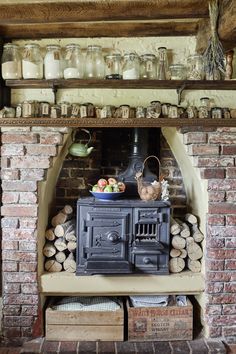 an old fashioned stove is in the middle of a room filled with logs and jars