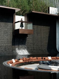 a man standing on top of a waterfall in the middle of a pool with couches