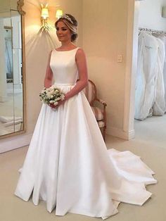 a woman standing in front of a mirror wearing a white dress and holding a bouquet