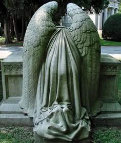 an angel statue wrapped in a blanket sitting on top of a cement slab next to a tree