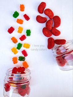 some gummy bears are in small glass jars and one is filled with candy hearts