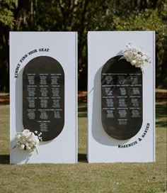 two black and white plaques with flowers on them in the middle of a grassy area