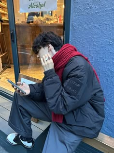 a man sitting on a bench looking at his cell phone in front of a store