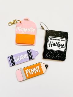 four different keychains with name tags attached to them on a white table top