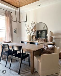 a dining room table with four chairs and a mirror on the wall in front of it