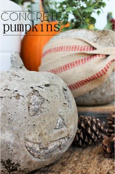 cement pumpkins sitting on top of a table next to pine cones and other decorations