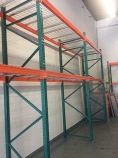 several shelves in a warehouse with orange and green shelving on each shelf, one is empty