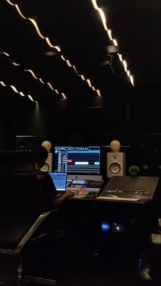 a man sitting at a desk in front of a computer monitor and sound mixing equipment