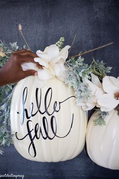 two white pumpkins with the word hello fall painted on them and flowers in front